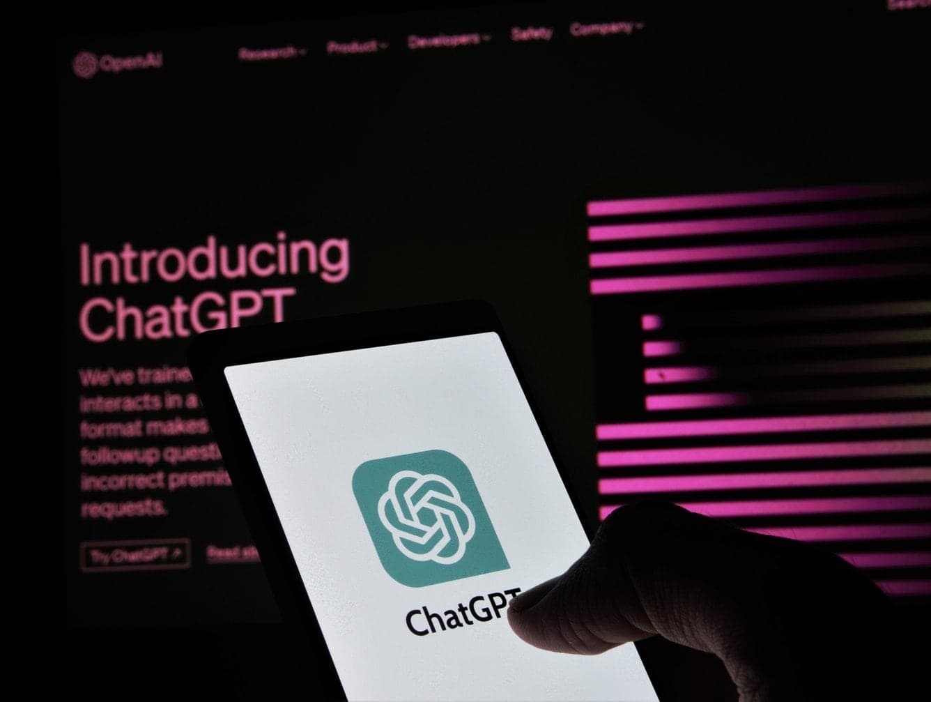 Smartphone mit ChatGPT-Logo vor dem Schriftzug „Introducing ChatGPT“