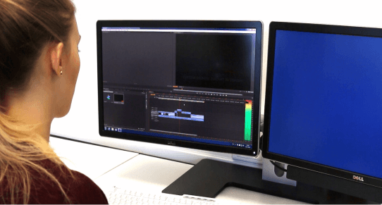 Studentin beim Videoschnitt an zwei Monitoren im Studium